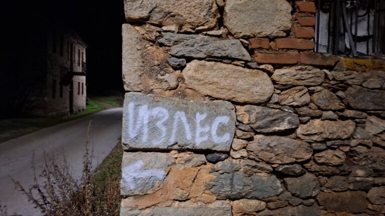 Графит со погрешно напишаниот збор ‘ИЗЛЕС’ на стар камен ѕид, симболична илустрација за текст за управувањето со културните институции.